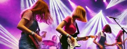Junge Frauen stehen auf der Bühne und spielen Gitarre