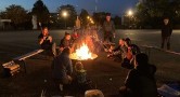 Menschen sitzen um ein Lagerfeuer