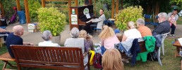 Menschen hören einem Pianisten am Klavier unter freiem Himmel zu