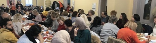 viele Menschen sitzen an Tischen und unterhalten sich